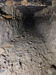 Hand-dug tunnel under concrete foundation for utility repair